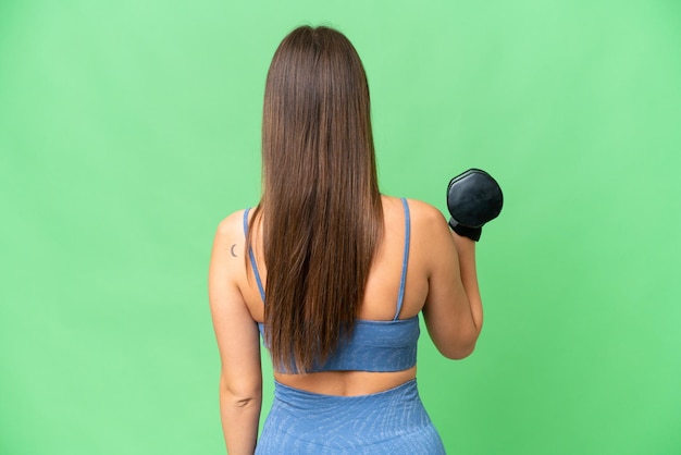 Young sport woman making weightlifting over isolated chroma key background in back position