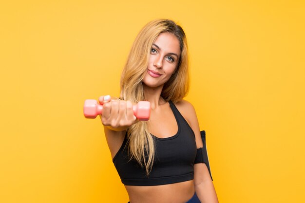 Young sport woman making weightlifting over isolated wall