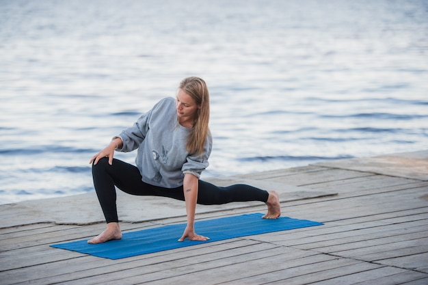 Молодая спортивная женщина упражнениями йоги на пляже