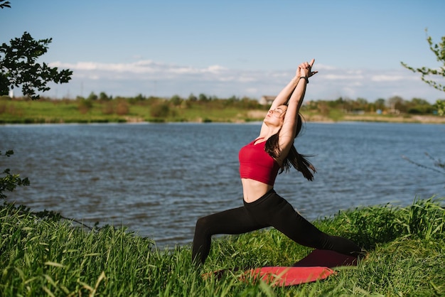 Young sport woman practicing yoga outdoors at the lakeshore
