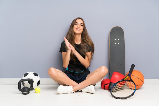 Photo young sport woman sitting on the floor applauding