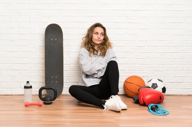 Young sport woman sitting on the floor thinking an idea