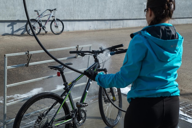 Young sport woman washing bicycle at selfservice car wash