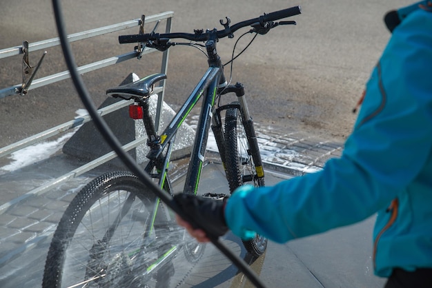 Young sport woman washing bicycle at selfservice car wash