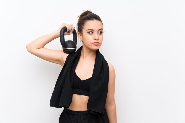 Young sport woman over white wall making weightlifting