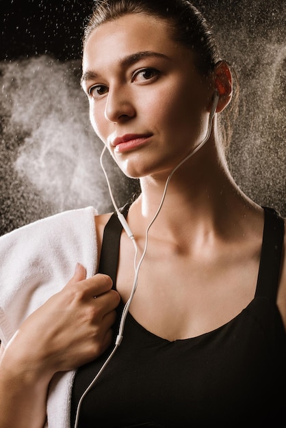 Young sport woman with earphones on black background