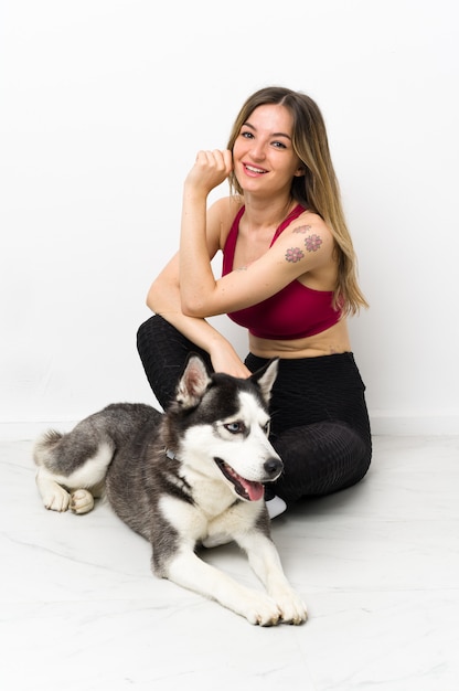 Young sport woman with her dog sitting on the floor