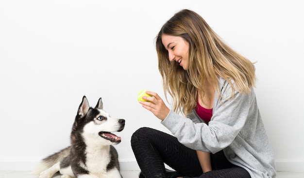 床に座っている彼女の犬を持つ若いスポーツ女性