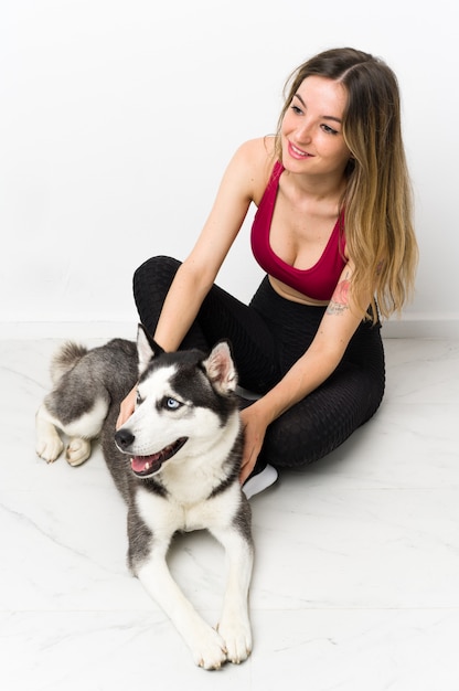 Молодая спортивная женщина со своей собакой сидит на полу