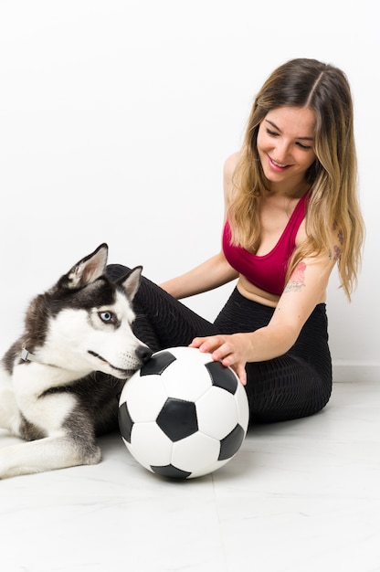 Foto giovane donna sportiva con il suo cane seduto sul pavimento