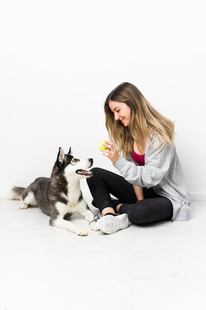 床に座っている彼女の犬を持つ若いスポーツ女性