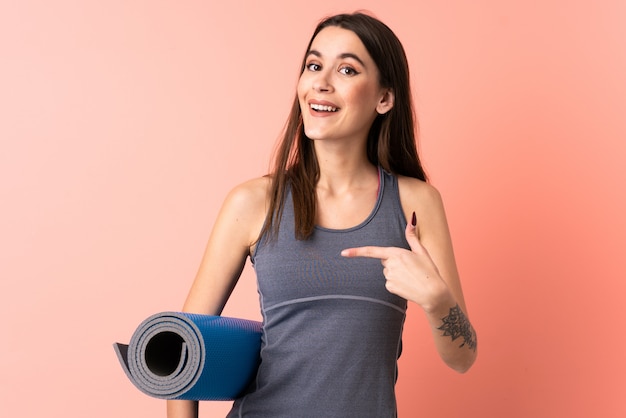 Young sport woman with mat over isolated wall with surprise facial expression