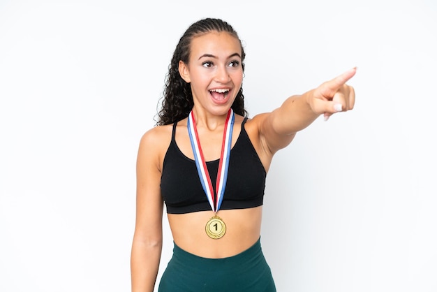 Young sport woman with medals isolated on white background pointing away