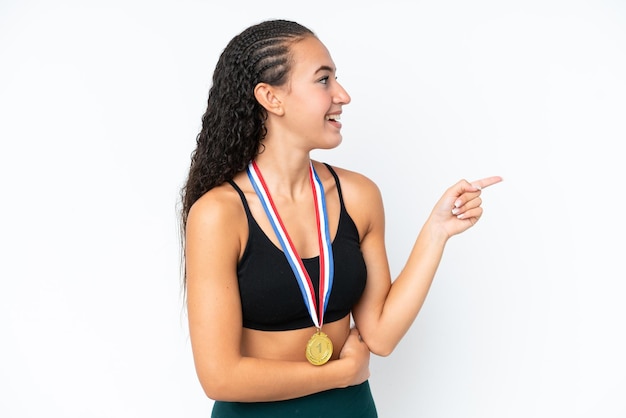 Young sport woman with medals isolated on white background pointing finger to the side and presenting a product