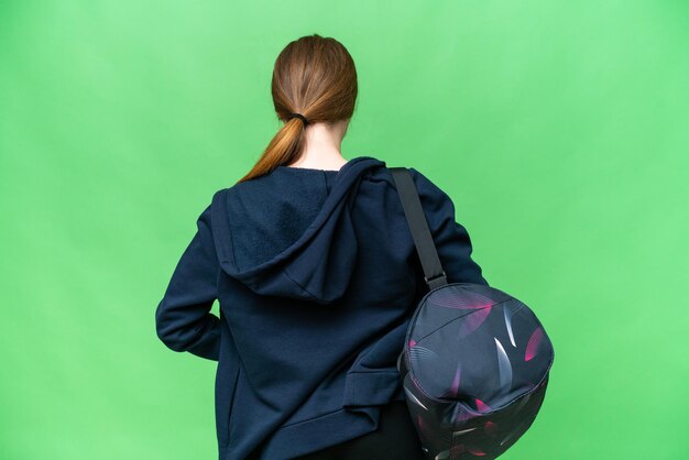 Молодая спортивная женщина со спортивной сумкой на изолированном фоне хроматического ключа в заднем положении