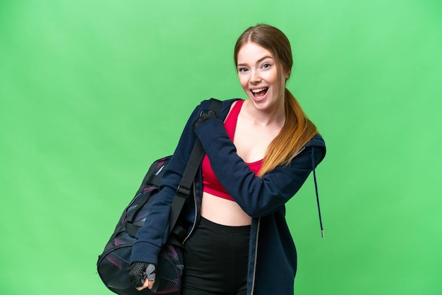 Young sport woman with sport bag over isolated chroma key background celebrating a victory