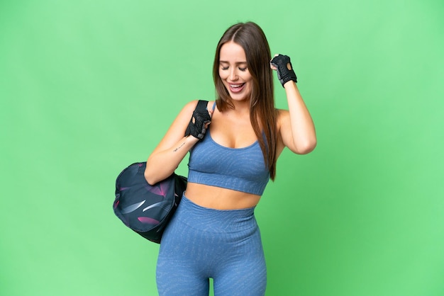 Young sport woman with sport bag over isolated chroma key background celebrating a victory