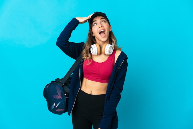 Young sport woman with sport bag isolated doing surprise gesture while looking to the side