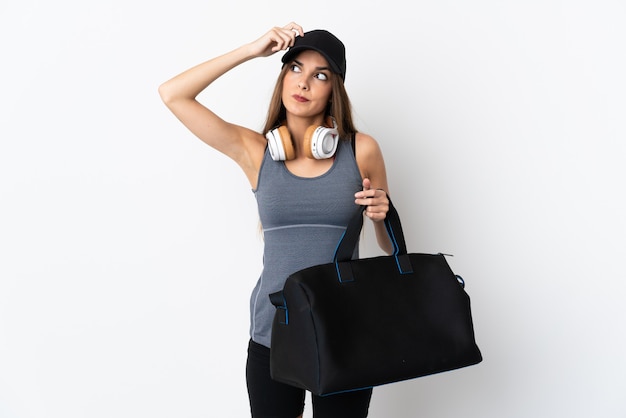 Young sport woman with sport bag isolated on white background having doubts and with confuse face expression