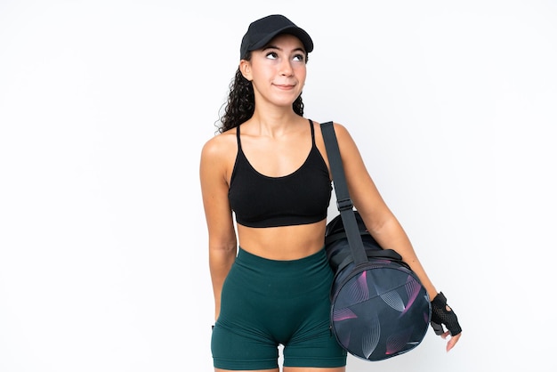 Young sport woman with sport bag isolated on white background and looking up