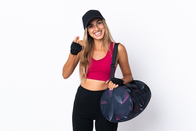 Young sport woman with sport bag over isolated white background making money gesture