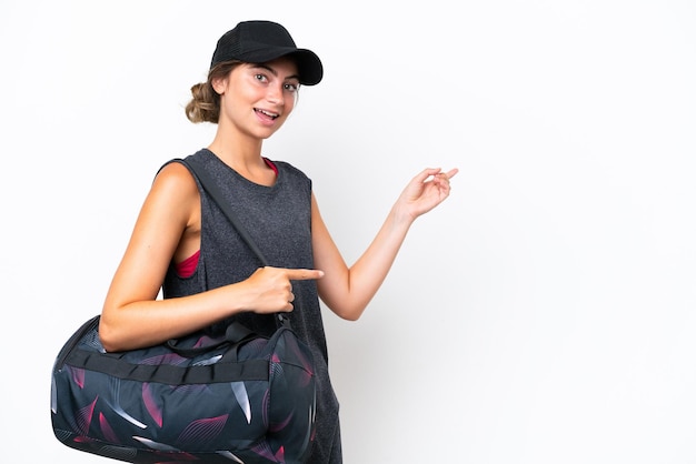 Young sport woman with sport bag isolated on white background pointing finger to the side and presenting a product