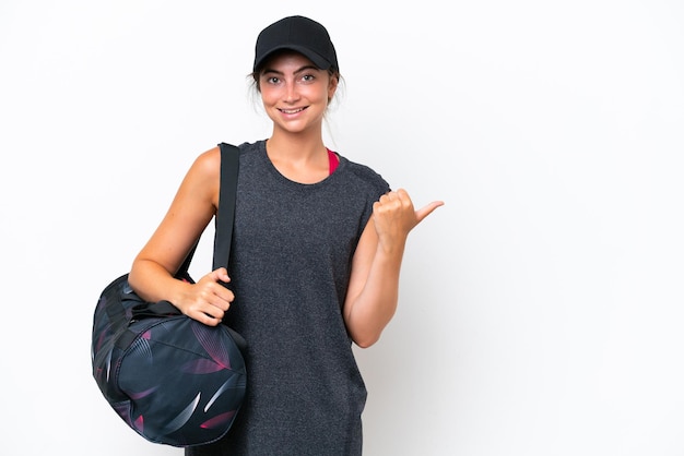 Young sport woman with sport bag isolated on white background pointing to the side to present a product