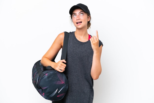 Young sport woman with sport bag isolated on white background pointing up and surprised