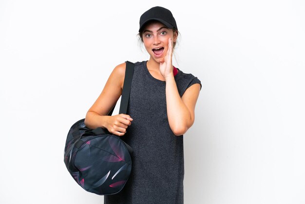 Young sport woman with sport bag isolated on white background shouting with mouth wide open