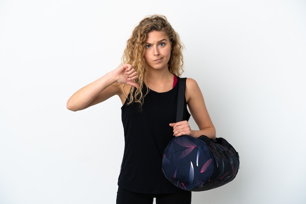 Young sport woman with sport bag isolated on white background showing thumb down with negative expression