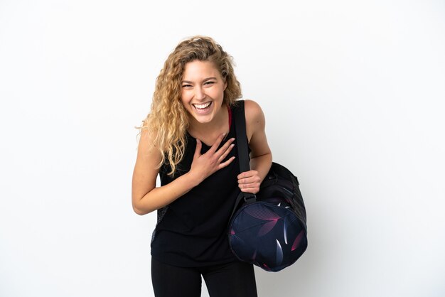 Young sport woman with sport bag isolated on white background smiling a lot