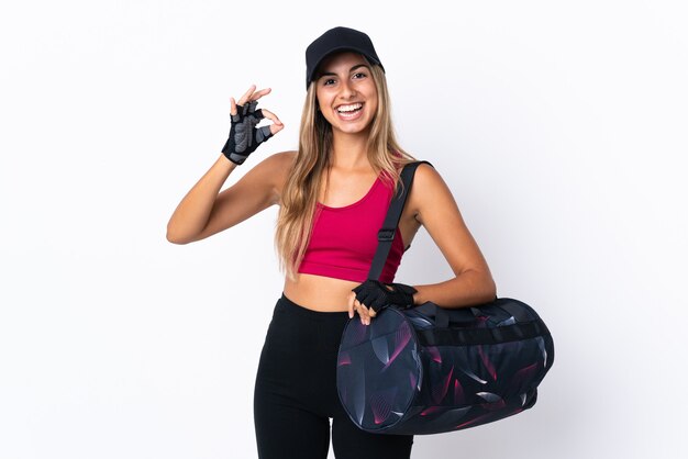 Young sport woman with sport bag over isolated white showing ok sign with fingers