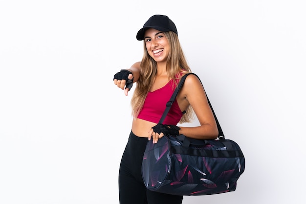 Young sport woman with sport bag over isolated white wall pointing front with happy expression