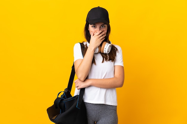 Young sport woman with sport bag isolated on yellow surprised and shocked while looking right
