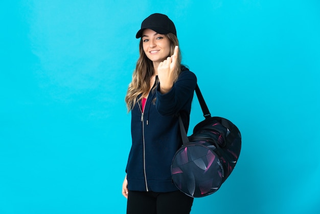 Young sport woman with sport bag posing isolated against the blank wall