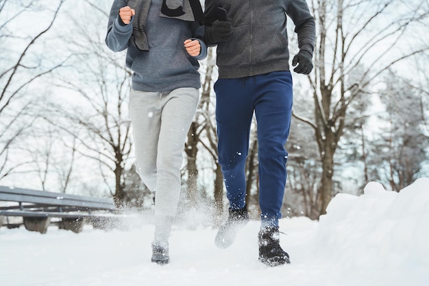 Young and sportive couple during winter jogging in snowy city park