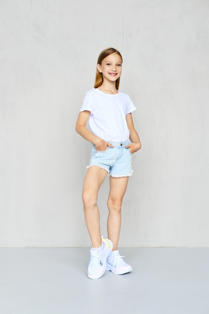 Young sportive girl in t-shirt and jeans shorts posing in studio