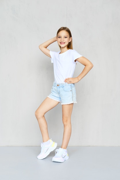 Young sportive girl in t-shirt and jeans shorts posing in studio