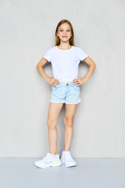 Young sportive girl in t-shirt and jeans shorts posing in studio