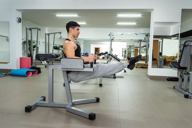 Young and sportive man making stretching exercises in gym