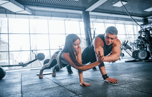 Young sportive people doing push ups together in the gym