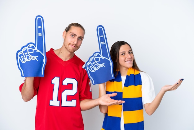 Photo young sports fan couple isolated on white background extending hands to the side for inviting to come