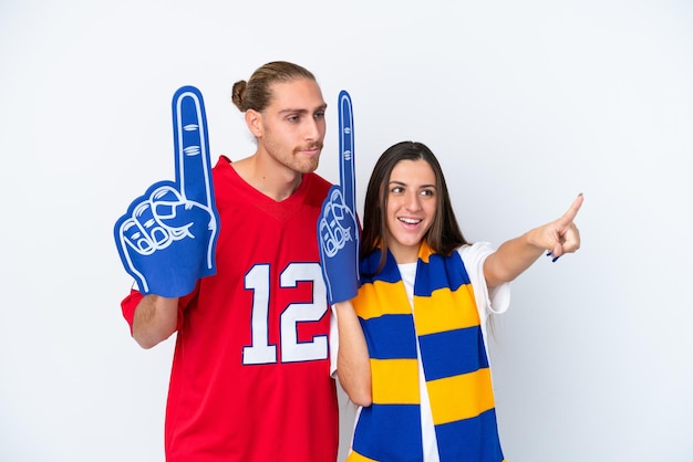 Young sports fan couple isolated on white background pointing\
to the side to present a product