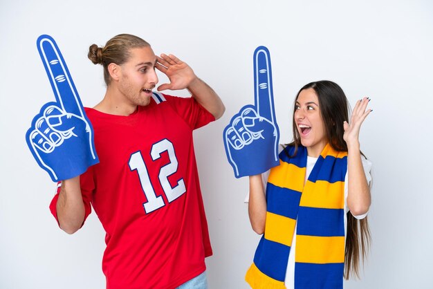 Young sports fan couple isolated on white background with surprise and shocked facial expression