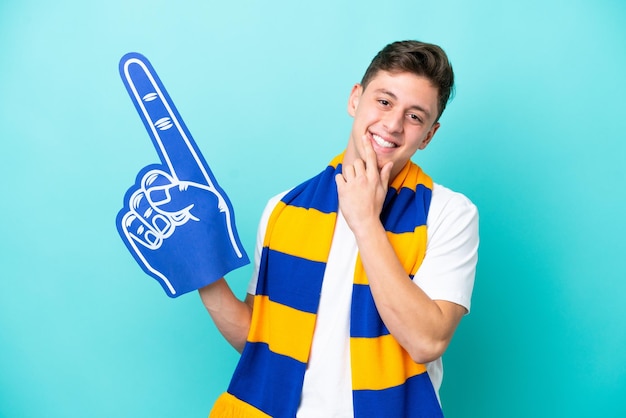 Young sports fan man isolated on blue background happy and smiling