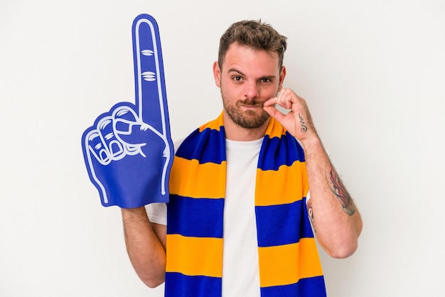 Young sports fan man isolated on white background with fingers on lips keeping a secret.