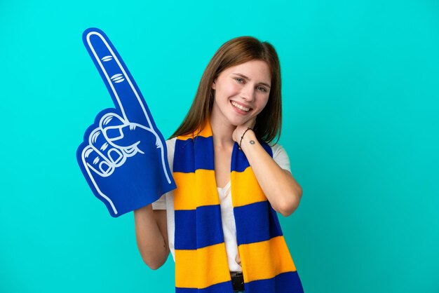 Young sports fan woman isolated on blue background laughing