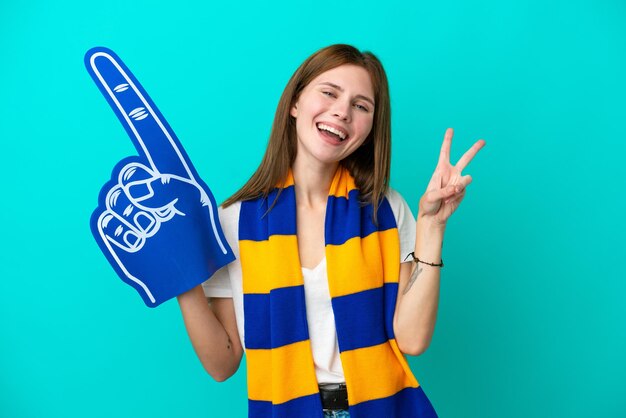 Young sports fan woman isolated on blue background smiling and showing victory sign