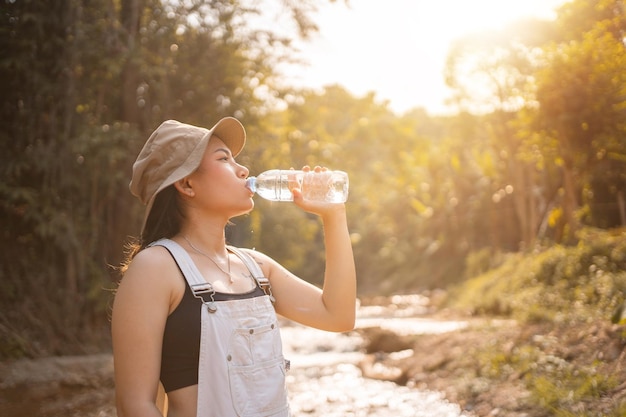Young sports girl drinks water from a bottle Woman is trail running
