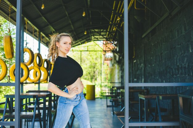 A young sports girl stands on a summer veranda Bright sunlight falls on the girl